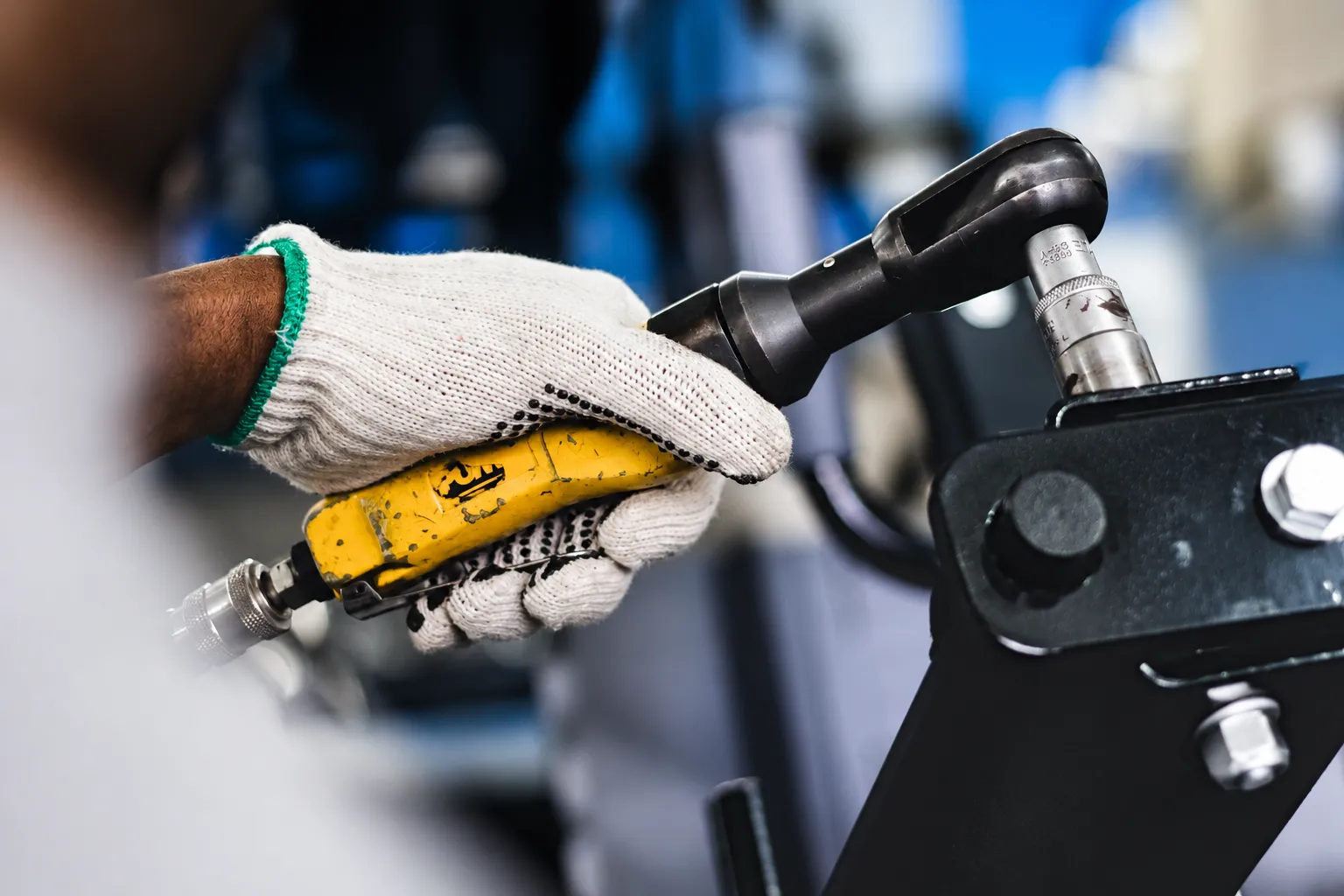Técnico desmontando a estrutura de uma máquina com ferramenta pneumática